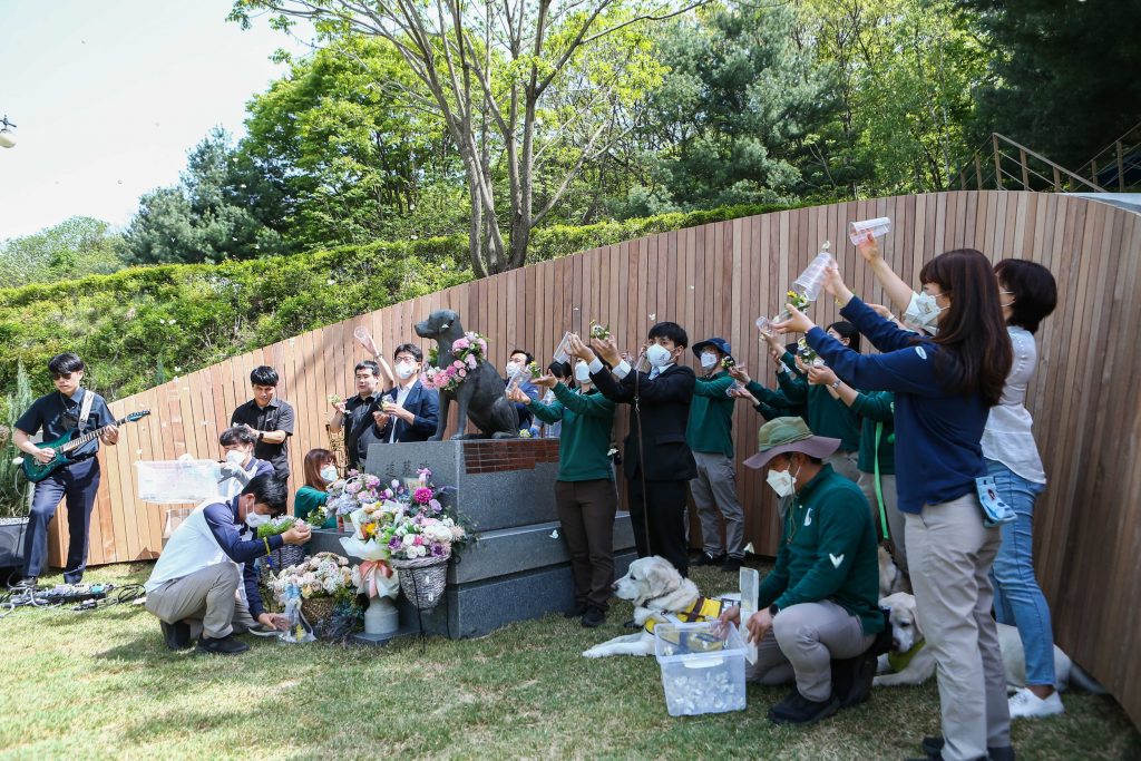 People releasing butterflies beside a guide dog memorial statue